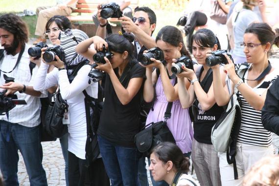 Ellerinde fotoğraf makineleri ile fotoğraf çekmeye çalışan kadın ve erkek fotoğrafçılar