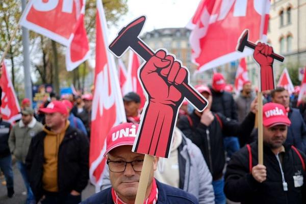 eylemde çekiç tutan bir el görselini taşıyan işçiler