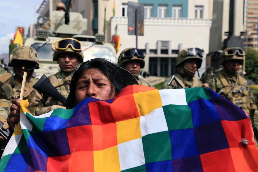 Bolivya'da askeri barikatı önünde darbeyi protesto eden yerli bir kadın ve elinde taşıdığı Whipala bayrağı