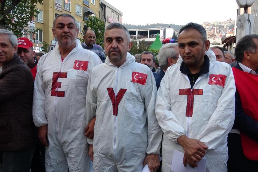 Basın açıklamasına katılan EYT mağduru üç kişi, üzerlerinde 'E', 'Y' ve 'T' harfleri bulunan tulumlarla yan yana dururken