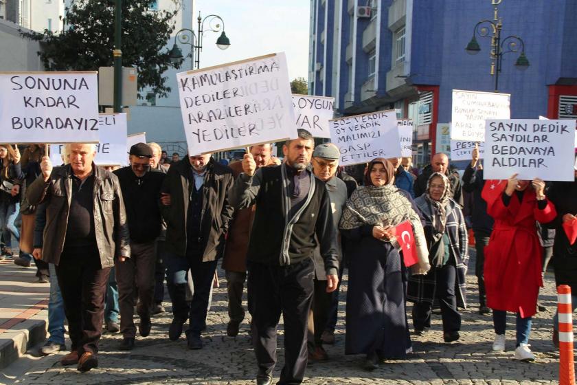 Vatandaşlar ellerinde dövizlerle kamulaştırma bedellerini protesto ediyor. 