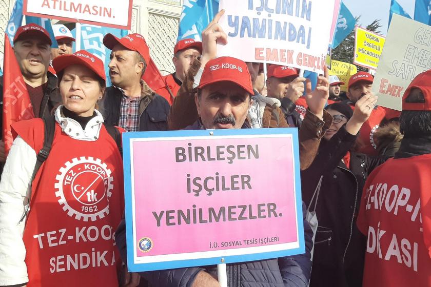 İstanbul Üniversitesi Beyazıt Kampüsü girişinde yapılan eylemde 'Birleşen işçiler yenilmezler' yazılı döviz tutan bir işçi