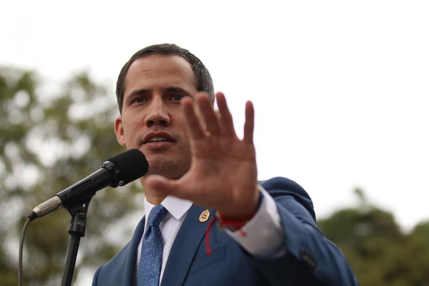 Juan Guaido gazetecilere açıklama yapıyor. Elini hayır anlamına gelecek şekilde kaldırmış.