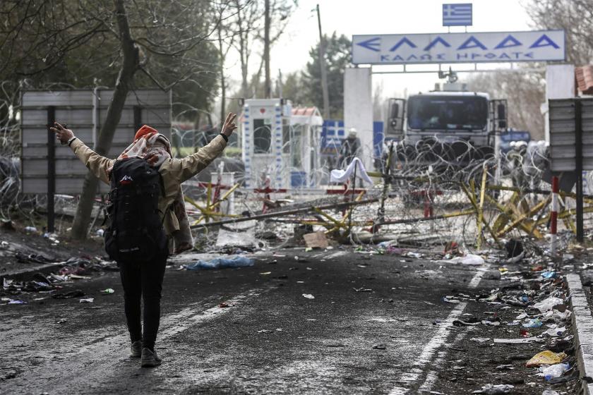 Yunanistan tarafından atılan gaz bombalarına karşı zafer işareti yapan mülteci