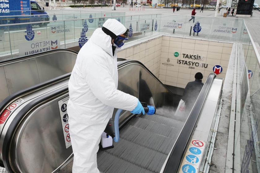 İstanbul Taksim metro istasyonunun girişlerinden birinde görveliler dezenfekte işlemi yaparken.