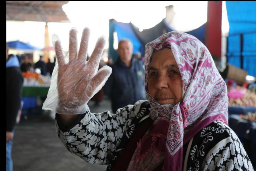 Koronavirüs salgını nedeniyle semt pazarında eldiven kullanarak satış yapan pazarcı kadın.