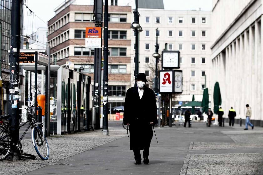 Almanya'da koronavirüs (Kovid-19) salgını dolayısıyla alınan önlemler sonrası boş bir caddede yüzünde maske ile yürüyen bir erkek.