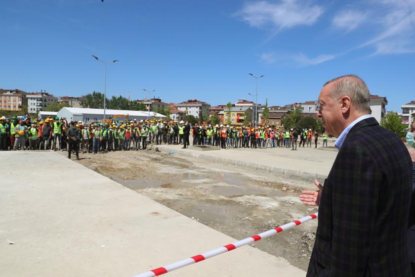 Cumhurbaşkanı Erdoğan'ın Sancaktepe'deki hastane inşaatını gezdiği sırada, yüzlerinde maske olmayan ve yan yana durmak zorunda kalan işçileri, araya çekilmiş olan güvenlik şeridinin arkasından selamladığı an.