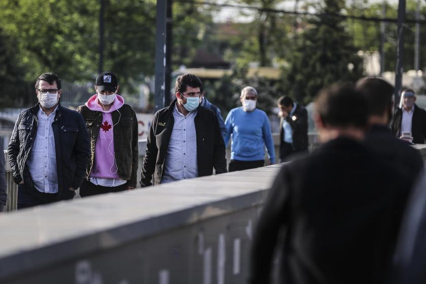 İstanbul'da toplu taşıma araçlarından çıkan yüzleri maskeli insanlar.