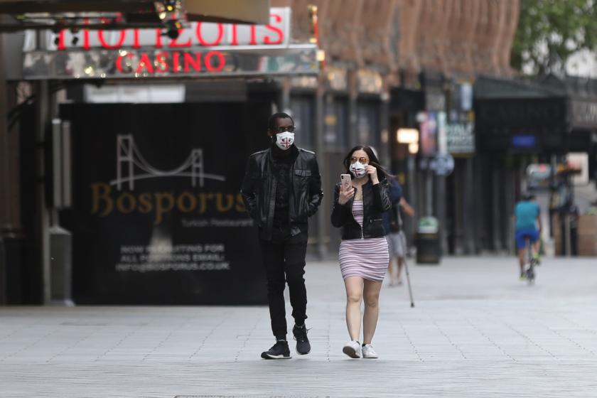 A man and a woman wearing face masks as a precaution against Coronavirus (Covid-19) walk in London, England