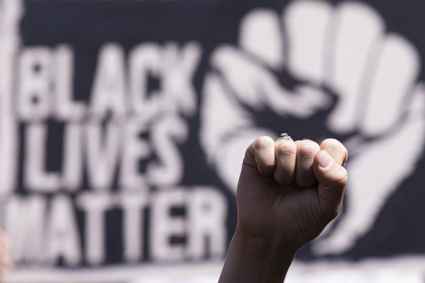 Sıkılı bir yumruk ve arka fonda black lives matter yazısı