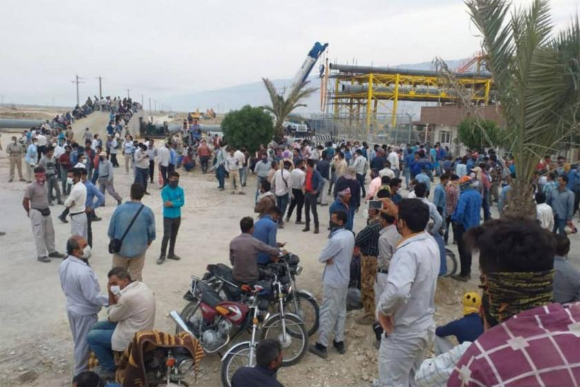 İran'da greve çıkan enerji işçileri, kalabalık halinde bir arada dururken.