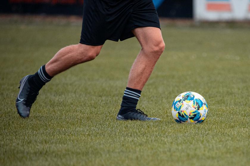 Futbol oynayan bir futbolcunun bacakları ve futbol topu.