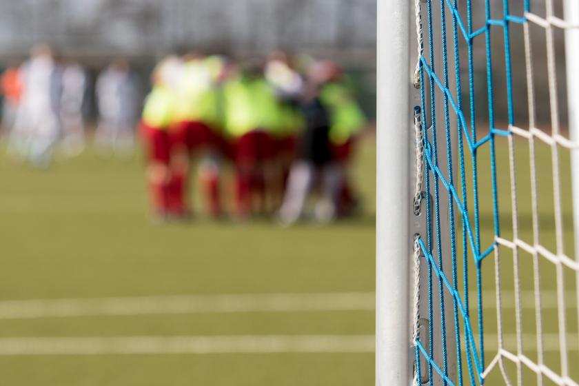 Futbol sahasında bir araya gelmiş ve uzakta ancak flu şekilde gözüken futbolcular.