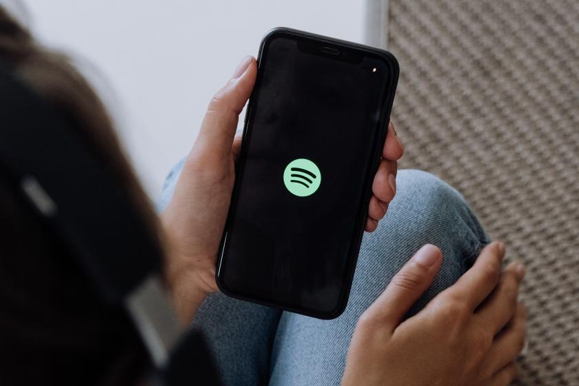 Telefonunda Spotify uygulamasını açan bir kadın fotoğrafı.