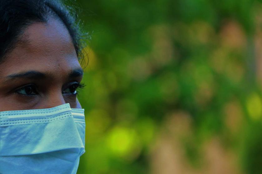 Yüzünde maske olan Afrikalı bir kadın, sağa doğru bakıyor