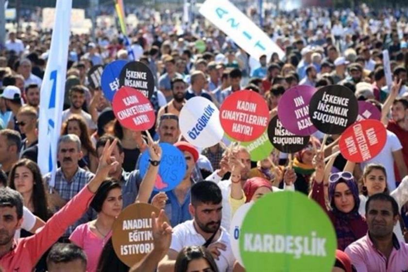 Ellerinde farklı taleplerin yazılı olduğu dövizlerle mitinge katılmış insanlar.