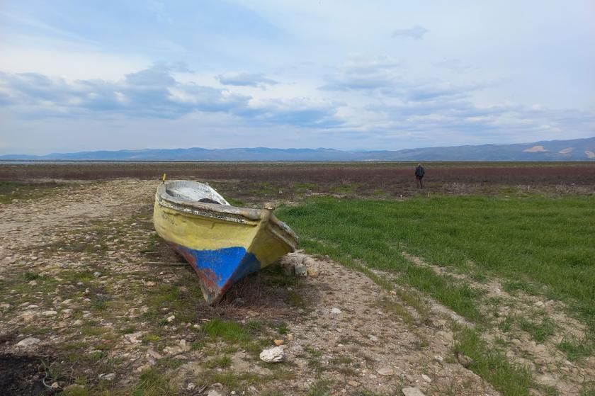 Marmara Gölü'nün kuruyan bölümünde bir kayık ve uzakta görünen bir adam. 