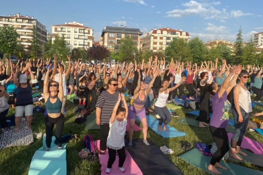 yoga yapan yüzlerce kadın ellerini havaya kaldırmış