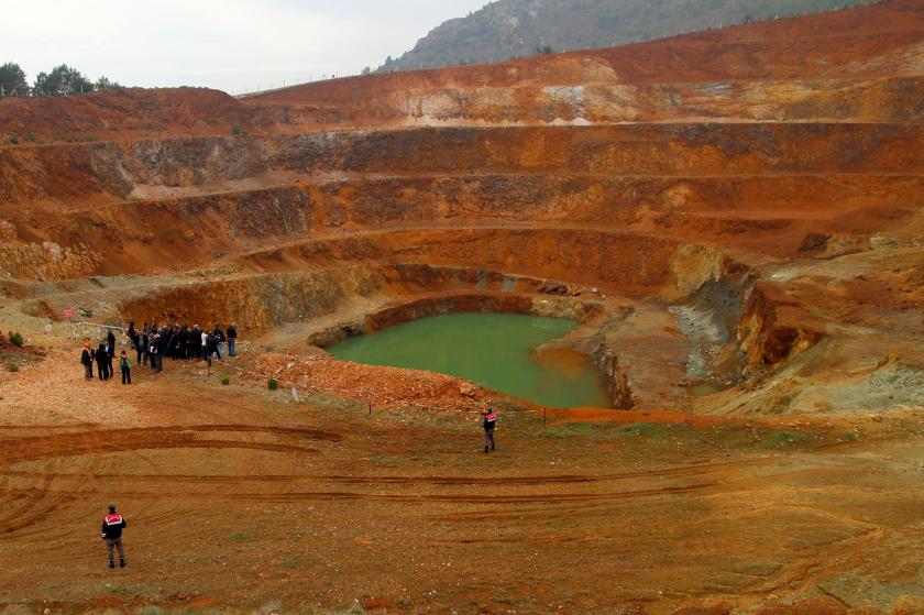 maden sahasında, kahverengi toprağın üzerinde, madene bakan insanlar