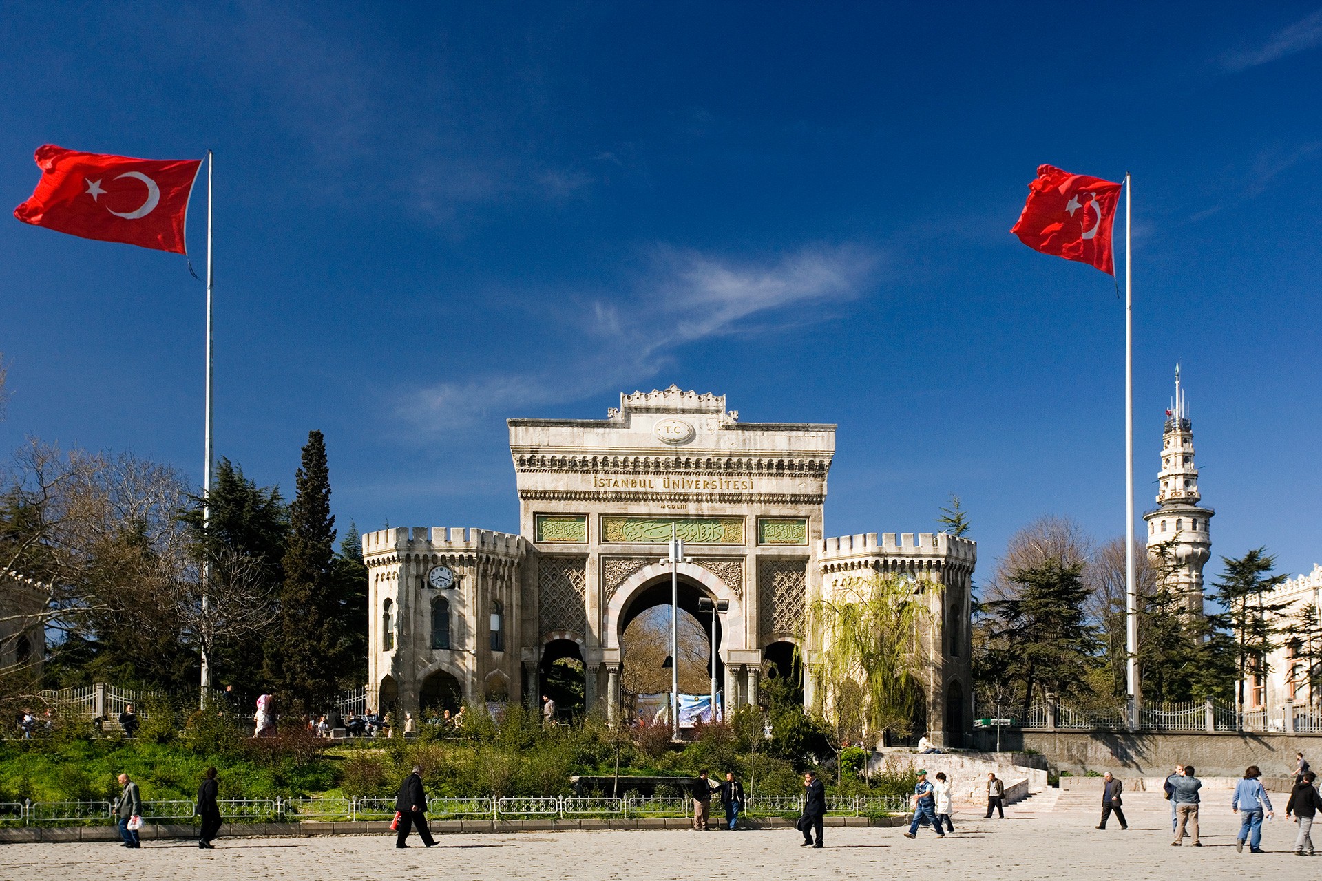 İstanbul Üniversitesi'nin tarihi kapısı ve meydanda yürüyen insanlar.