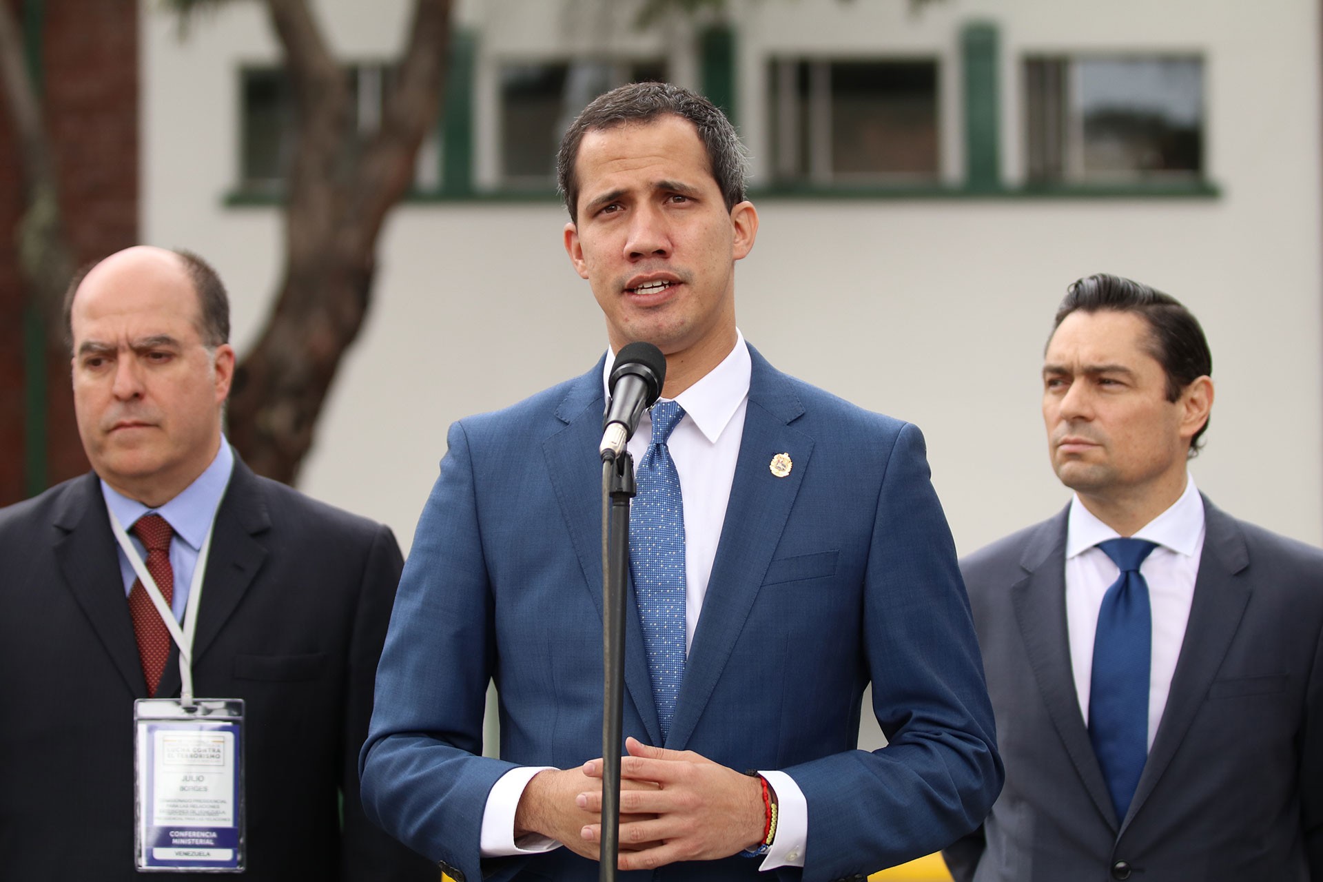 Juan Guaido gazetecilere açıklama yapıyor. Sağında ve solunda ekibinden kişiler var.