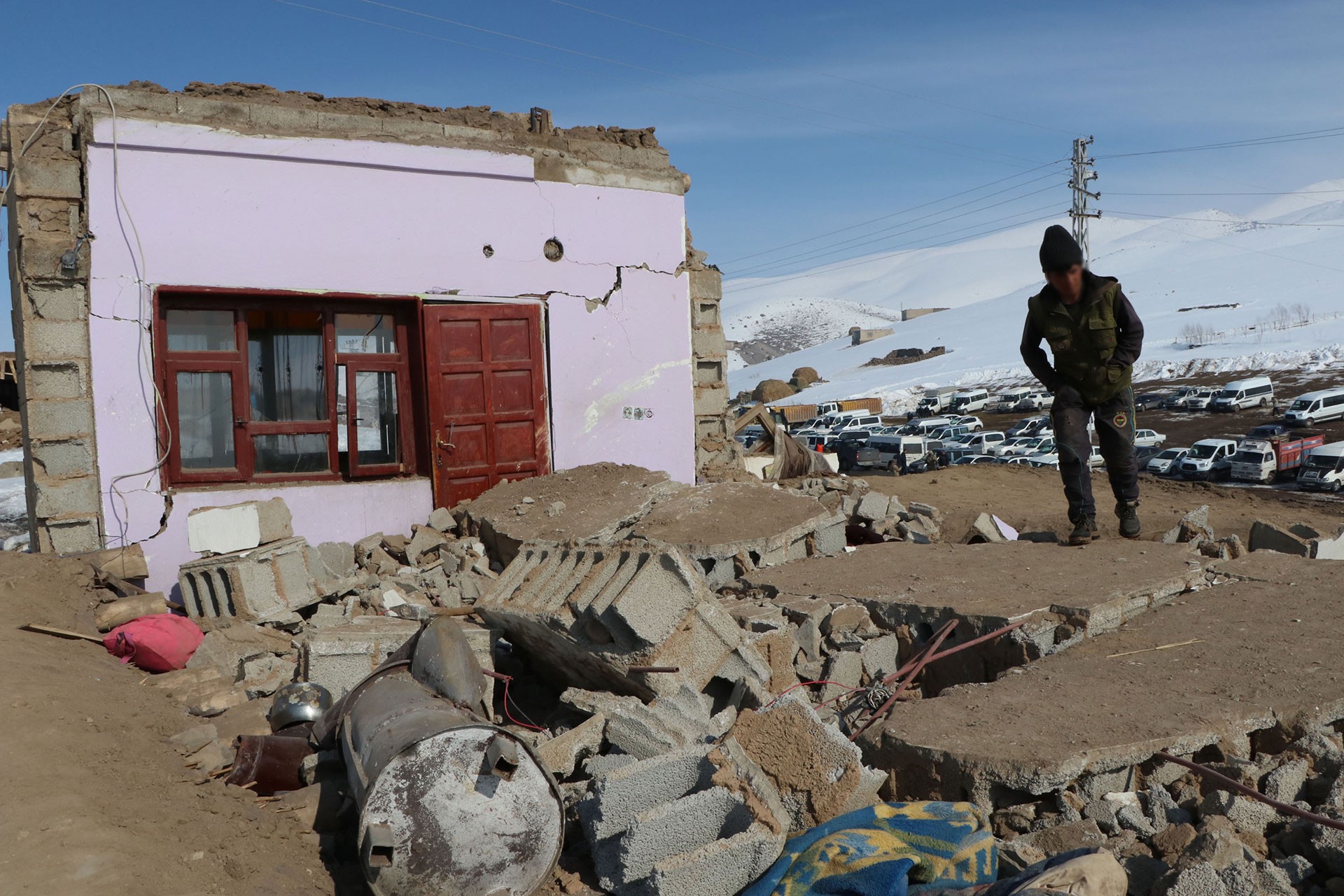 Yıkılan evin ardında kalanlar (önde), ağır hasarlı ev (solda) ve bir depremzede