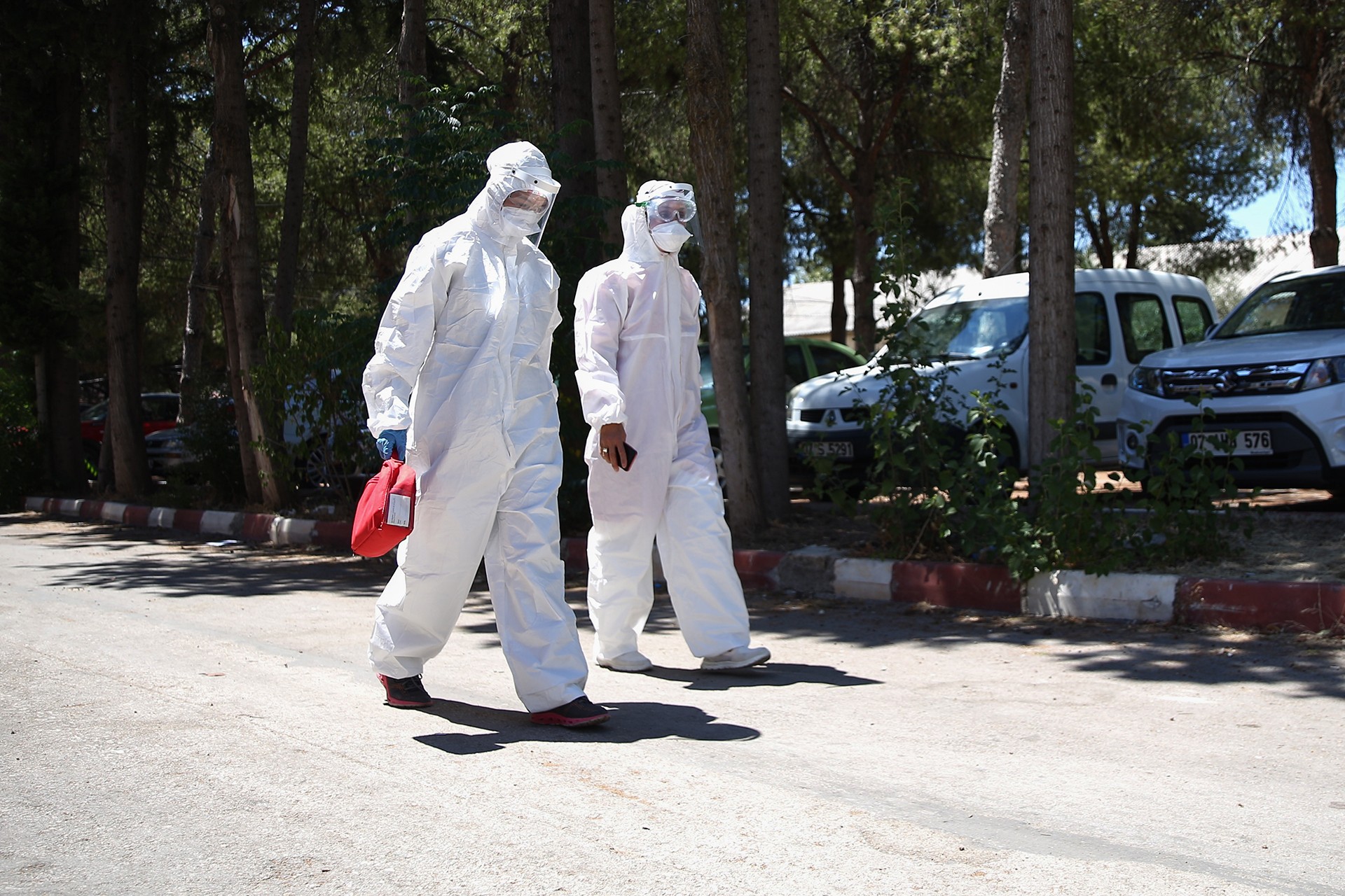 Antalya'da filyasyon ekibinde görevli iki personel koruyucu giysileri ve maskeleri ile sokakta yürürken.