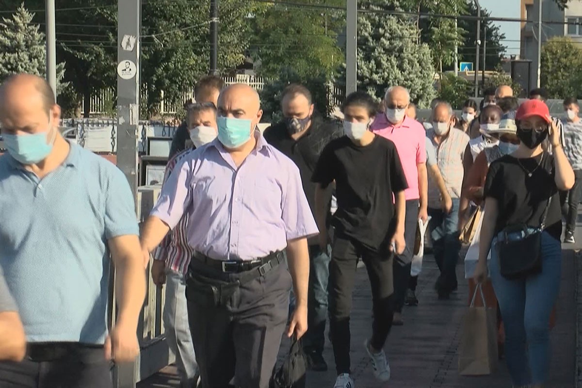 Kalabalık bir metrobüs durağında maskeli insanlar