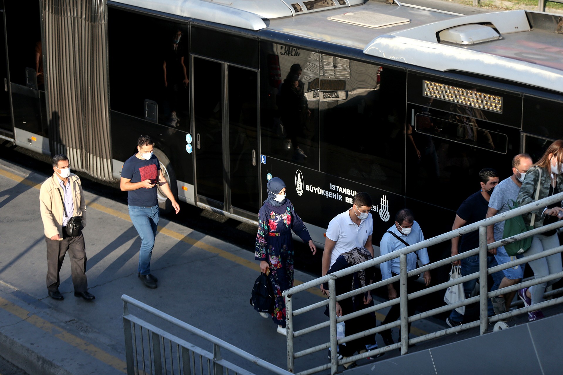 Metrobüs istasyonunda araçtan inen ve yüzlerinde maske bulunan yurttaşlar.