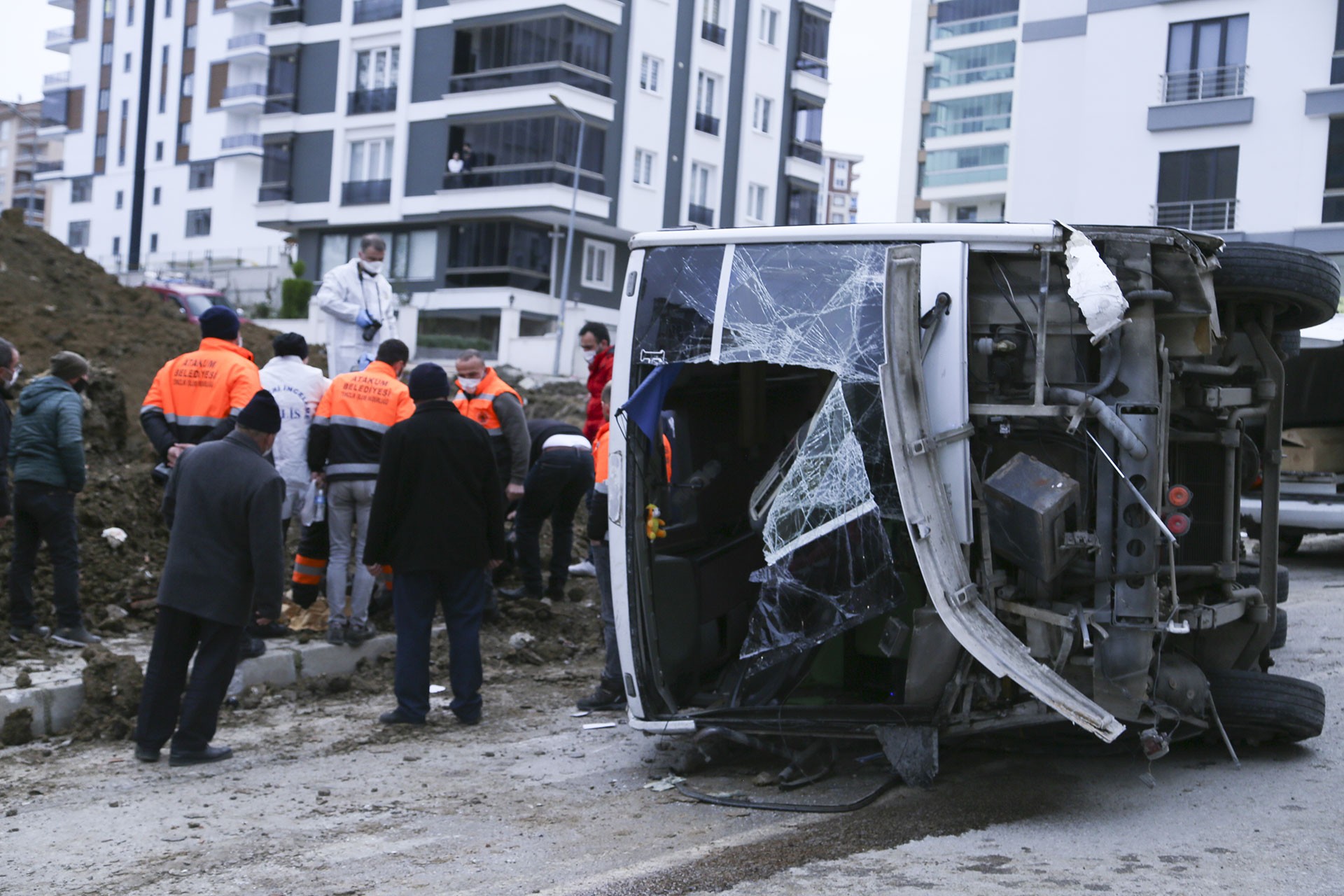 Devrilen midibüs ve çevresinde insanlar.