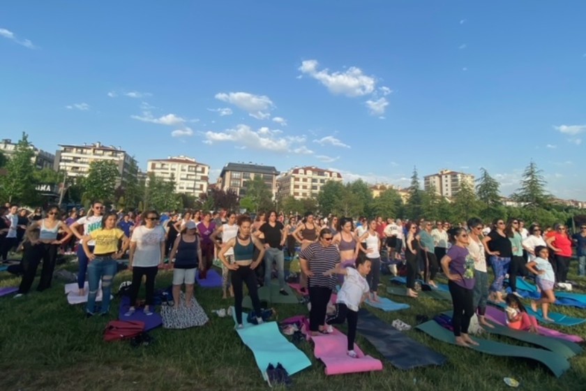 yoga yapan yüzlerce kadın ellerini havaya kaldırmış