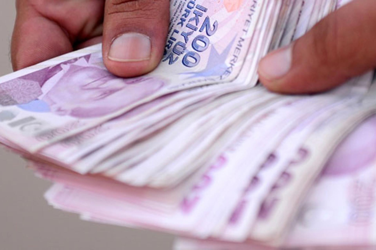 Bir kişinin iki eli arasında tutulan ve 200 Türk lirası banknotlarından oluşan bir para destesi. Para maaş TL ücret ödeme aylık ikramiye