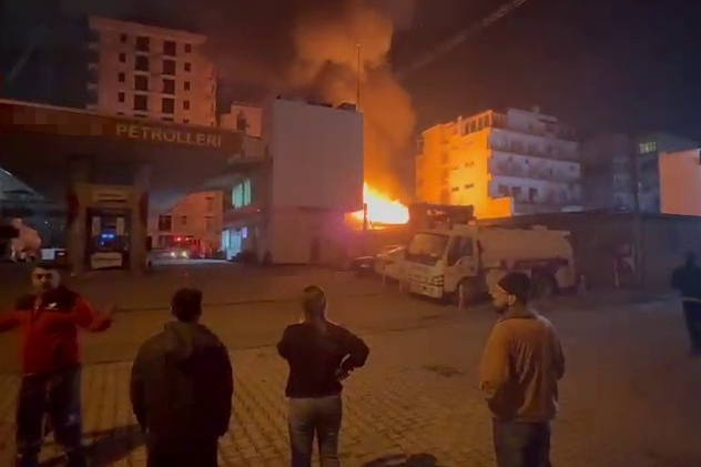 Hatay'ın İskenderun ilçesinde yapı malzemeleri satılan iş yeri yanıyor, insanlar yangını izliyor